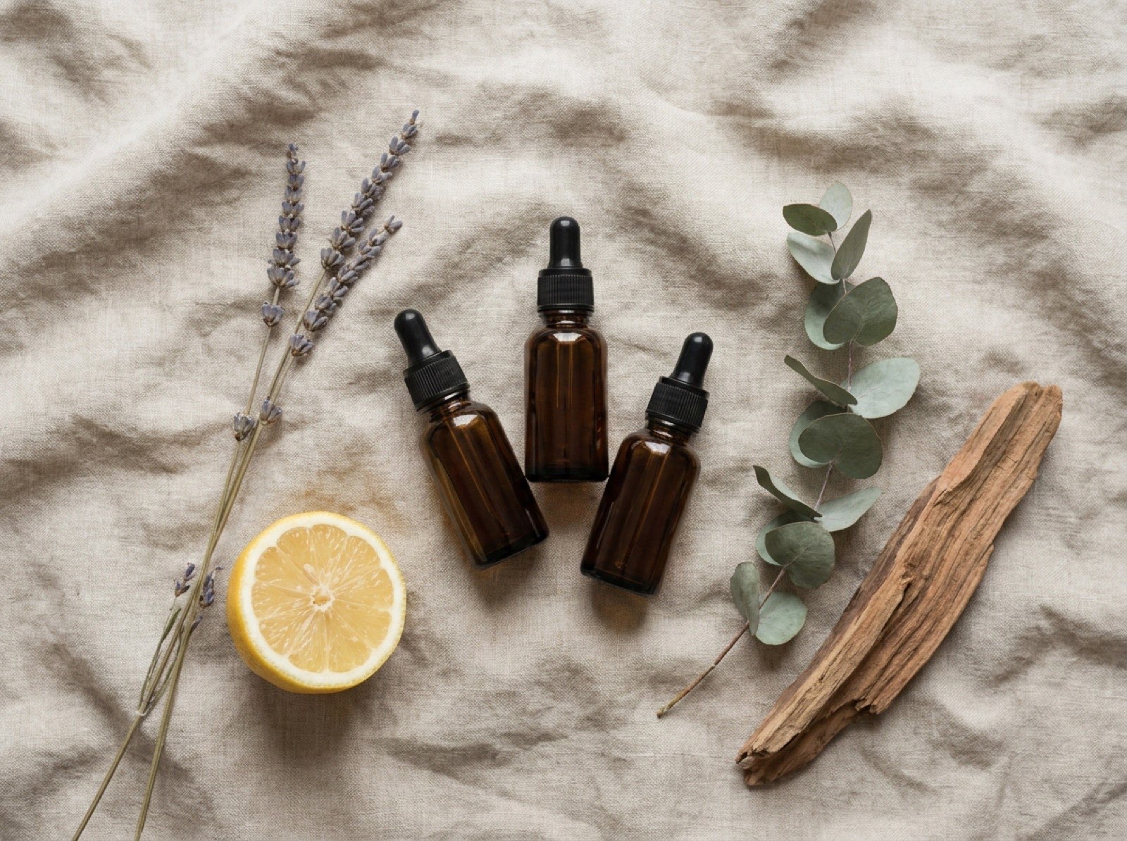Drei Fläschchen ätherisches Öl mit Lavendel, Zitrone, Eukalyptus und Sandelholz